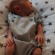 Kylo is registered to the contest to win money with this photo: baby, infant, child, cushion, star_pattern, overalls, soft_toy, hand, foot, face, indoor, furniture, fabric, looking_sideways, cute, newborn, relaxing, resting, person, portrait