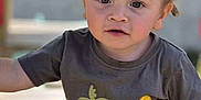 Kurtys a rejoint le concours — aidez-le/la à gagner de superbes lots ! toddler, child, curly_hair, outdoor, tshirt, dinosaur, sitting, wooden_surface, face, expression, young_child, casual_clothing, daylight, person, cute, innocent, skin, eyes, portrait, baby