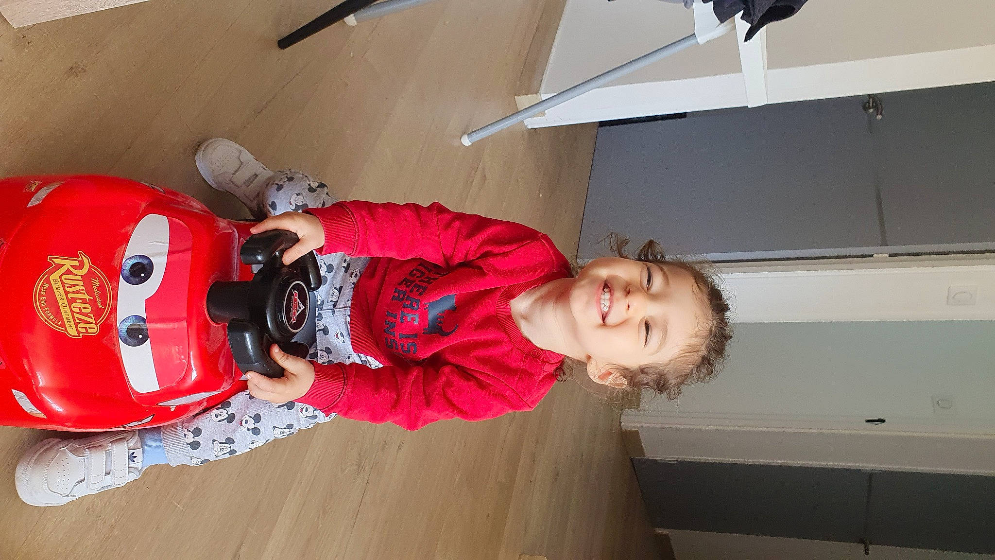 Giuliann participe au concours pour gagner de l'argent avec cette photo : carmine, child, flooring, fun, hardwood, helmet, jacket, joy, person, personal_protective_equipment, red, room, smile, toddler, varnish, wood, wood_flooring, wood_stain