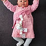 Laïane participe au concours pour gagner de l'argent avec cette photo : baby, infant, pink_dress, white_tights, plush_toy, pacifier, raised_arms, lying_down, cute, child, indoors, portrait, smiling, soft_toys, clothing, person, adorable, baby_accessories, happy, young_child
