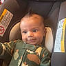 baby, infant, child, car_seat, portrait, smiling, wide_eyed, sitting, camouflage, onesie, clothing, hair, face, indoors, vehicle, safety_strap, car_interior, photography, cute, happy