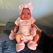 Kinsley is registered to the contest to win money with this photo: baby, infant, child, portrait, sitting, pink, bow, headband, onesie, mittens, booties, smiling, wide_eyed, bed, blanket, bedroom, indoor, fashion, cute, lifestyle