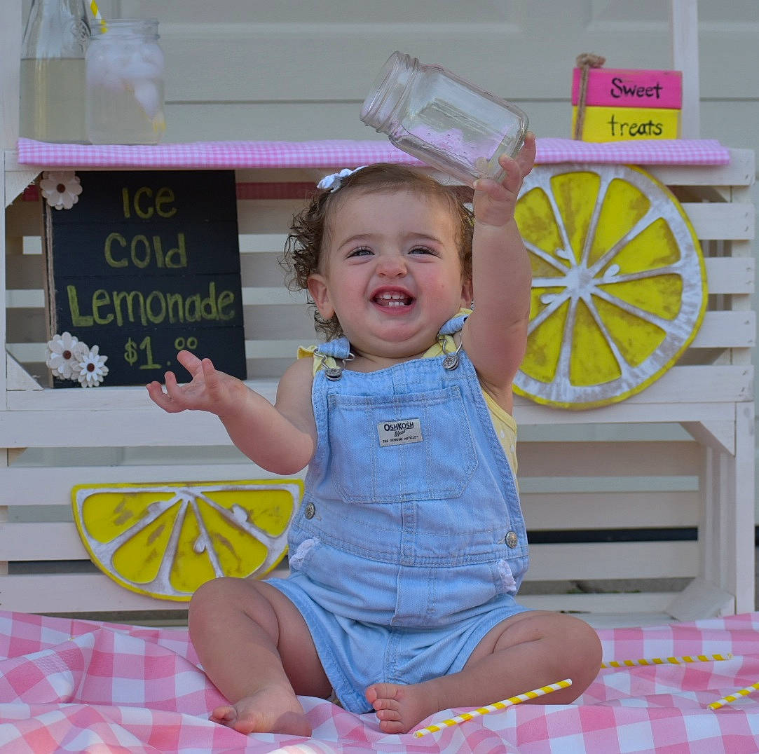 Ellie is registered to the contest to win money with this photo: automotive_wheel_system, baby, baby_toddler_clothing, child, design, event, fun, happy, joy, leisure, magenta, pattern, person, pink, play, purple, room, sitting, smile, tire