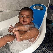 Kashton is registered to the contest to win money with this photo: baby, bathtub, bath, foam, bubbles, child, skin, water, blue_backrest, smile, happy, indoor, tiled_wall, floor_tiles, person, cute, infant, wet, playful, sitting