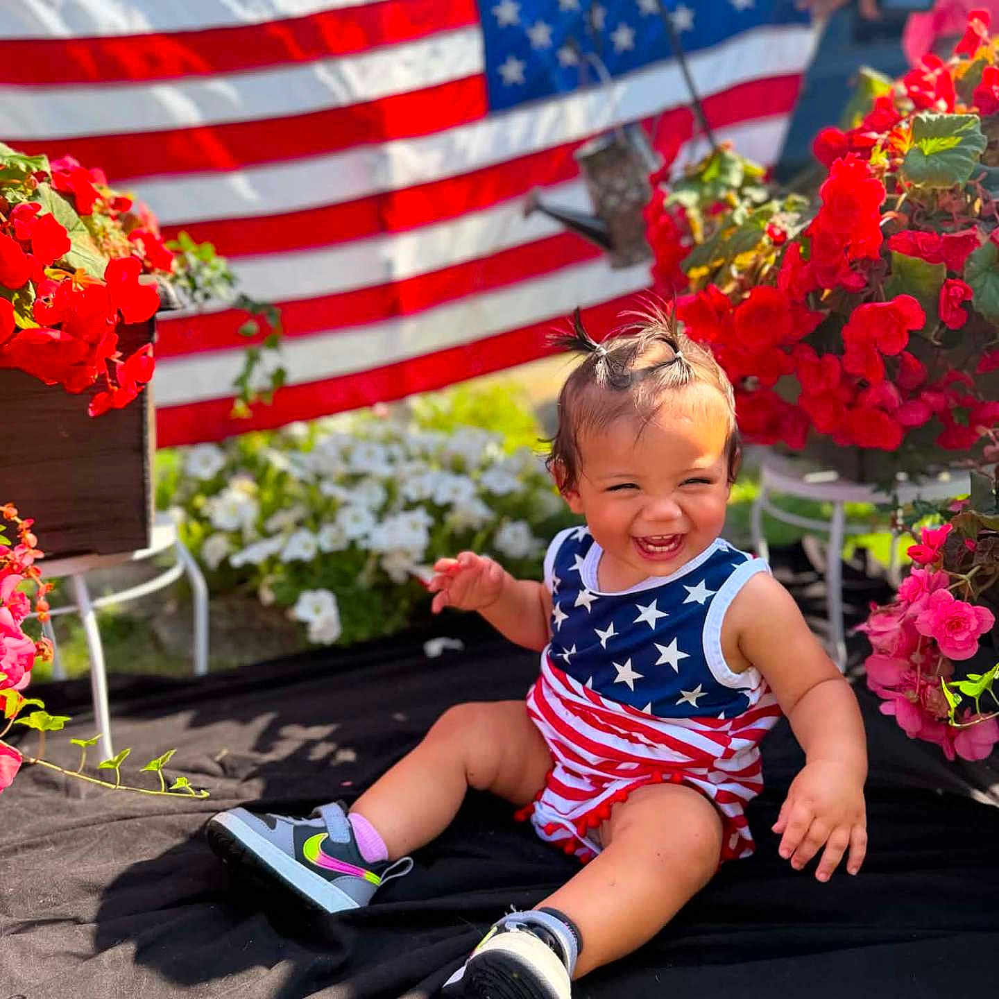 Nova Ann joined the competition — help win amazing prizes! toddler, child, smile, happy, american_flag, red_flowers, outdoor, sunlight, sitting, clothing, shoes, grass, plants, portrait, baby, celebration, cute, nature, fun, summer