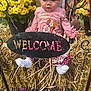 Nova Ann is registered to the contest to win money with this photo: baby, child, pink_clothing, bow, hay, flowers, yellow_flowers, orange_flowers, welcome_sign, autumn, fall, outdoor, decor, seasonal, cute, sitting, portrait, person, celebration, festive