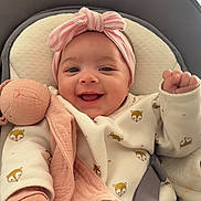Alma a rejoint le concours — aidez-le/la à gagner de superbes lots ! baby, smiling, headband, pink, plush_toy, baby_seat, clothing, cute, infant, happy, child, toddler, indoors, face, person, soft_toy, seat_belt, white, patterned_clothing, closeup
