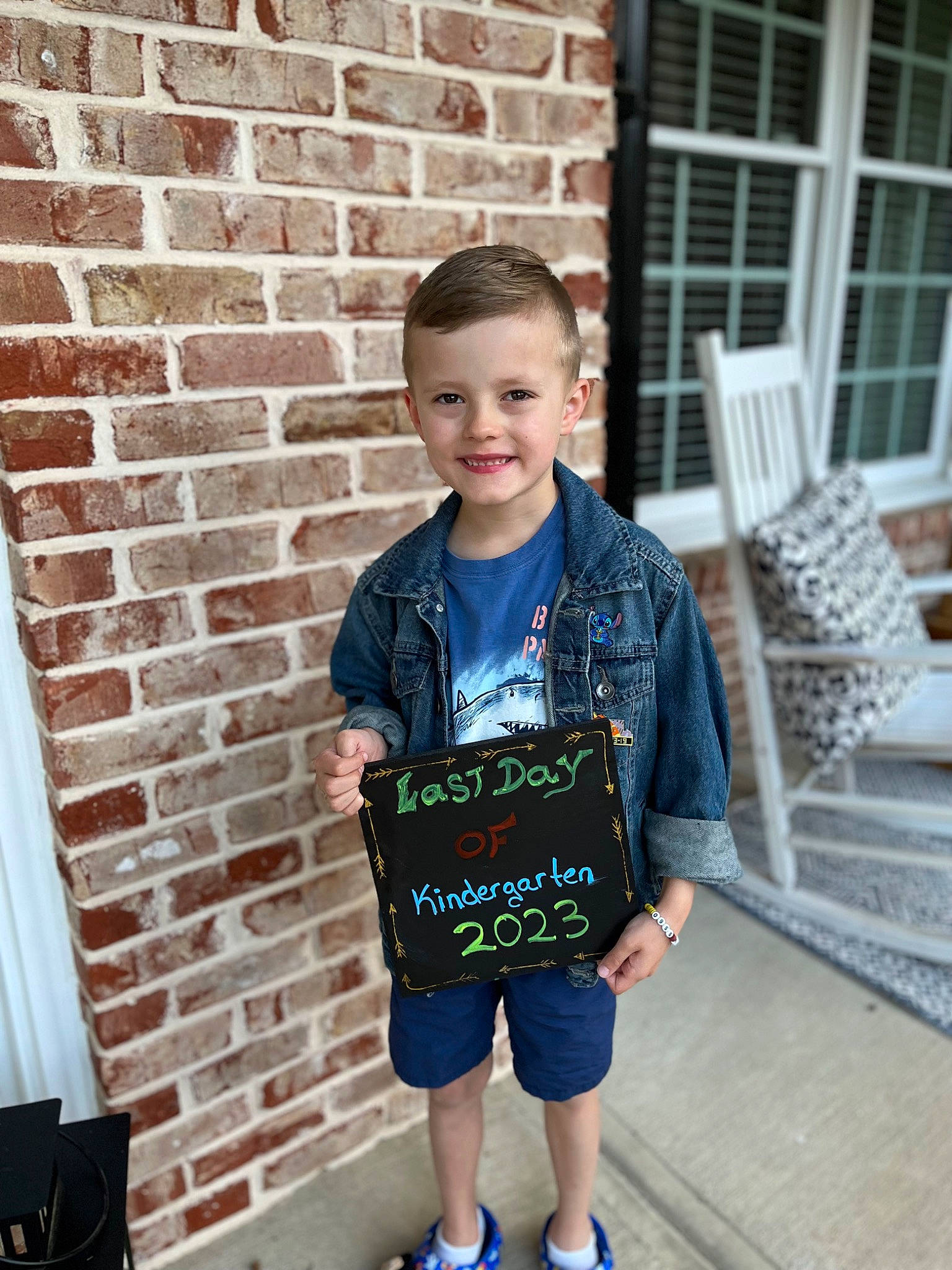 Dylan is registered to the contest to win money with this photo: brick, brickwork, chair, child, electric_blue, event, fun, happy, joint, joy, leisure, outdoor_furniture, pattern, person, recreation, sitting, sleeve, smile, standing, t_shirt