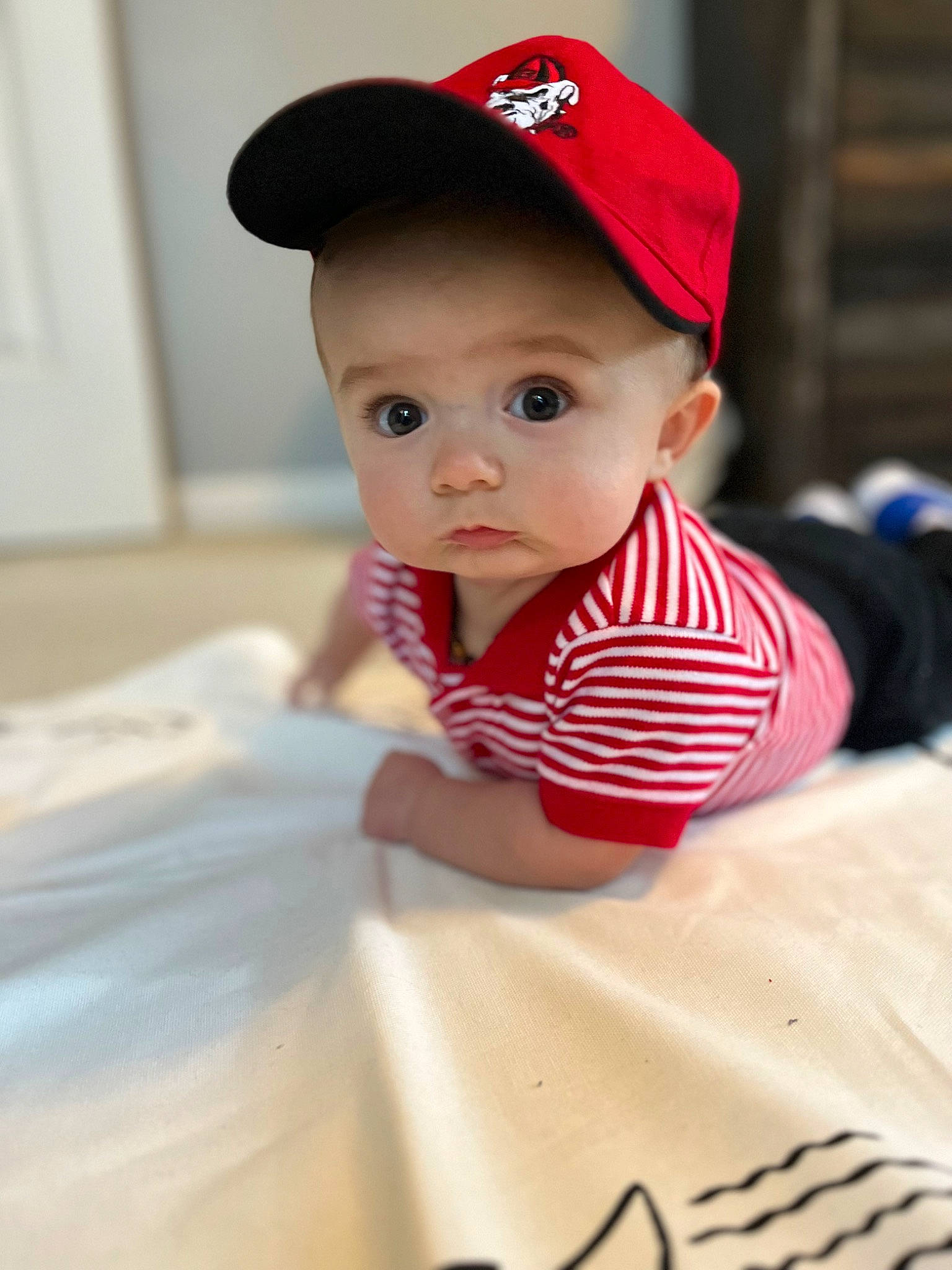 Conor is registered to the contest to win money with this photo: baby, baby_toddler_clothing, baseball_cap, cap, carmine, cheek, child, cricket_cap, facial_expression, fashion_accessory, fun, happy, hat, headwear, lip, neck, person, sitting, skin, sleeve