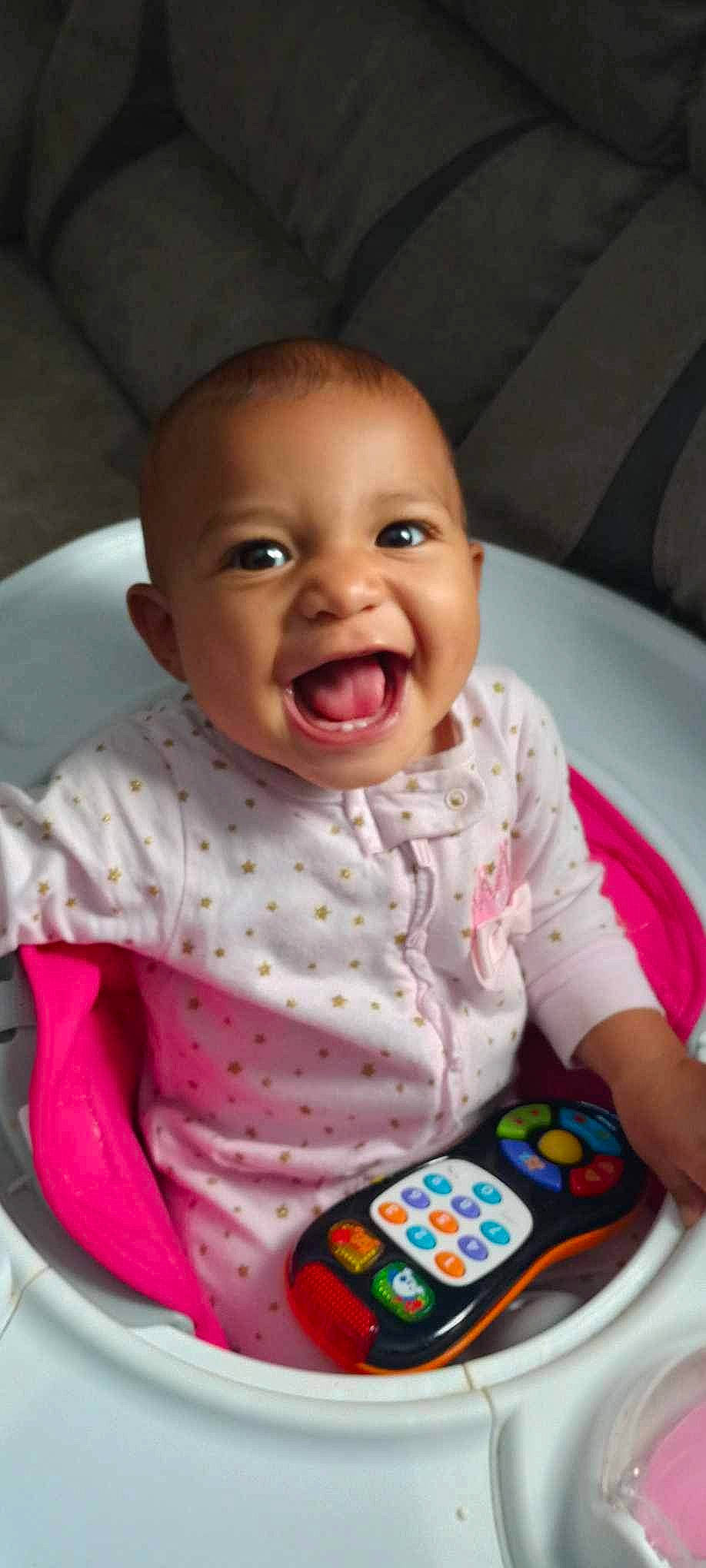 Kiara is registered to the contest to win money with this photo: baby, baby_laughing, baby_playing_with_toys, baby_products, baby_safety, baby_toddler_clothing, cheek, child, comfort, happy, linens, nose, pattern, person, pink, room, skin, sleeve, smile, t_shirt