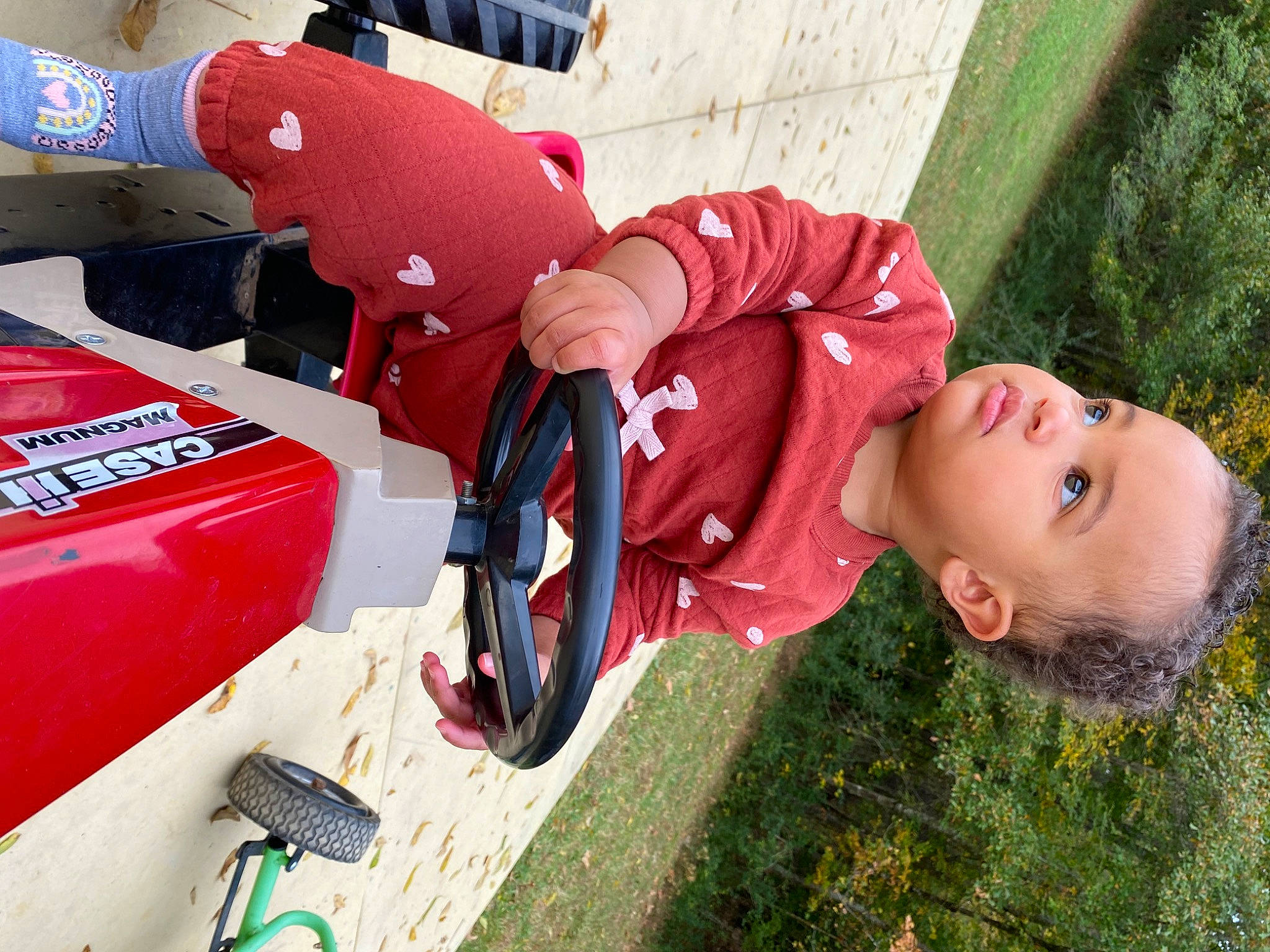 Fallon Hope is registered to the contest to win money with this photo: auto_part, automotive_exterior, automotive_tire, automotive_wheel_system, baby, bumper, carmine, child, fun, grass, green, leisure, motor_vehicle, person, personal_protective_equipment, plant, recreation, red, tire, toddler