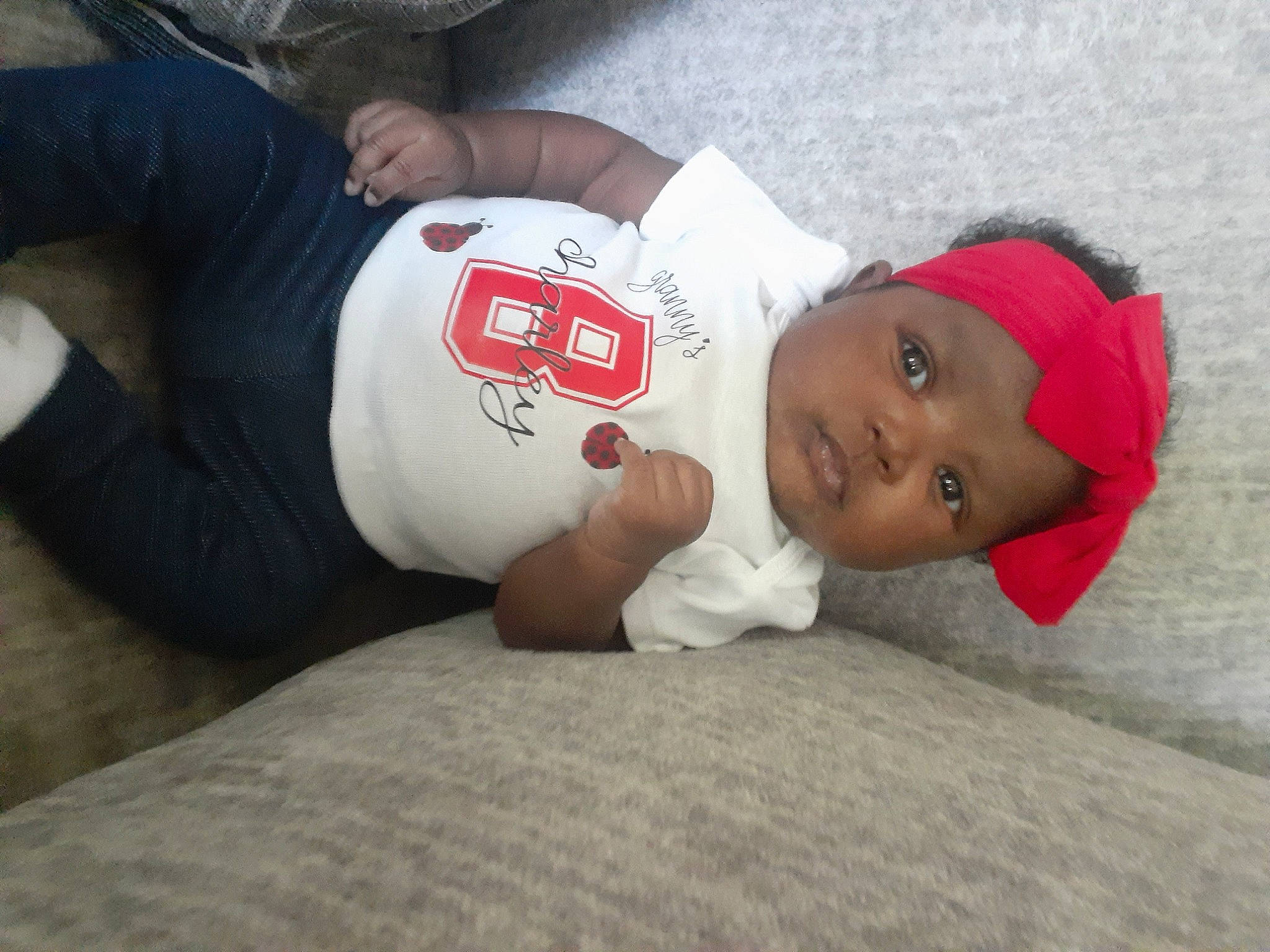 Amiri is registered to the contest to win money with this photo: baby, baby_toddler_clothing, cap, carmine, child, comfort, elbow, fur, grass, hat, headwear, linens, person, sitting, sleeve, t_shirt, toddler