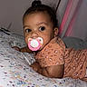 Eleanor joined the competition — help win amazing prizes! baby, pacifier, bed, floral_bedspread, curtains, patterned_clothing, indoor, child, portrait, sleepwear, small_bun, cute, lying_down, room, framed_photo, soft_lighting, infant, looking_away, cozy, young_child