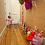 Anaia Amari joined the competition — help win amazing prizes! toddler, child, hallway, wood_floor, door, balloons, plush_toys, party_hats, pink_outfit, celebration, indoor, wall, toy_lineup, barefoot, curious_expression, colorful, stuffed_animals, flooring, birthday, decorations