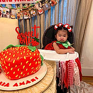 Anaia Amari joined the competition — help win amazing prizes! toddler, high_chair, strawberry_cake, birthday_party, cake, child, decoration, banner, ribbons, curtains, table, plate, red_dress, hair_bows, celebration, food, indoor, face, smile, person