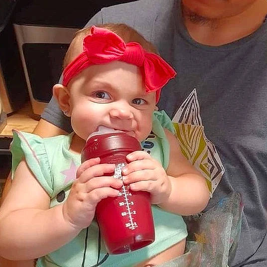 Thea is registered to the contest to win money with this photo: cheek, child, cool, drinkware, eyelash, finger, fluid, happy, headwear, helmet, lip, mouth, muscle, nail, neck, person, plastic_bottle, skin, sleeve, t_shirt