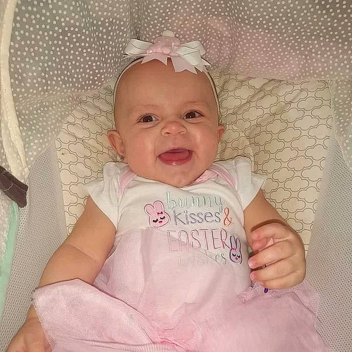 Thea is registered to the contest to win money with this photo: baby, baby_toddler_clothing, cheek, chin, comfort, eye, eyebrow, happy, head, iris, linens, lip, pattern, person, pink, product, skin, sleeve, smile, textile