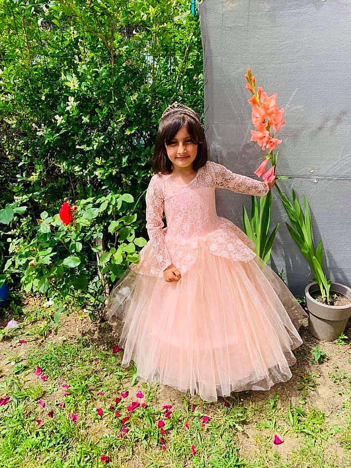 Manahil participe au concours pour gagner de l'argent avec cette photo : baby_toddler_clothing, bridal_party_dress, child, day_dress, dress, embellishment, event, flower, formal_wear, grass, happy, headpiece, joy, peach, people_in_nature, person, petal, pink, plant, ruffle