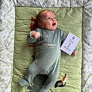 Tom participe au concours pour gagner de l'argent avec cette photo : baby, infant, onesie, blanket, card, face, expression, lying_down, green, pattern, celebration, milestone, cute, child, newborn, soft, clothing, person, indoors, happy