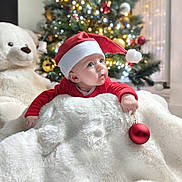 Luciana participe au concours pour gagner de l'argent avec cette photo : baby, blanket, celebration, child, christmas_lights, christmas_tree, cute, decorations, festive, holiday, holiday_season, indoors, ornament, present, red_clothing, santa_hat, smiling, soft_texture, teddy_bear, winter