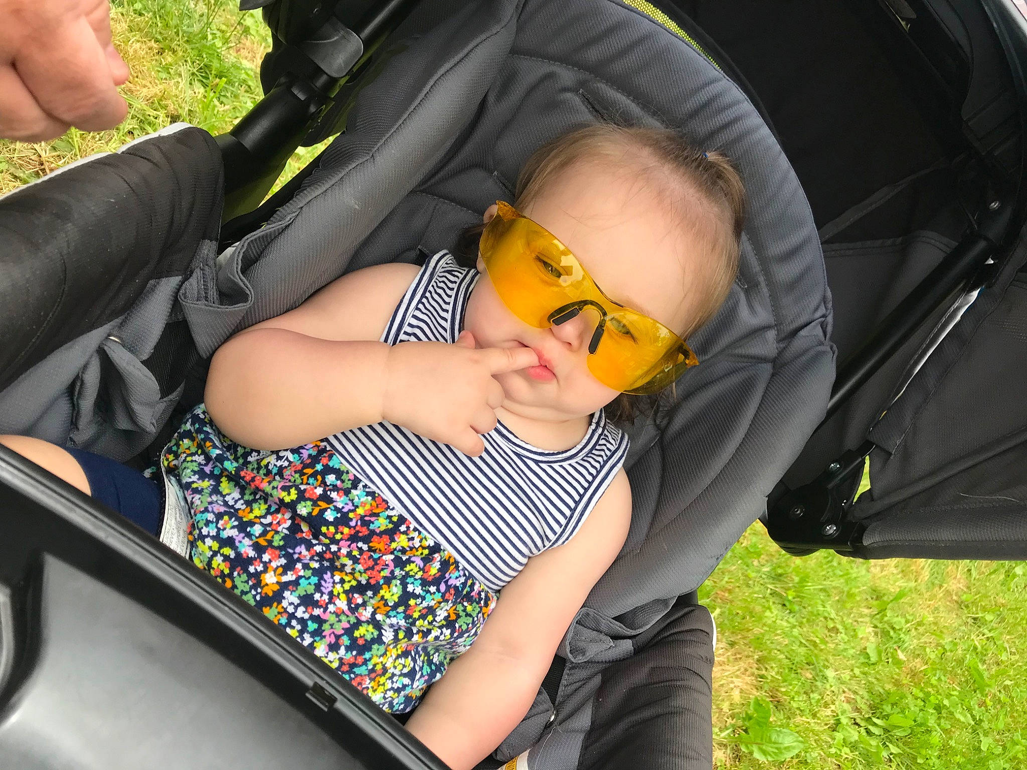 Grace is registered to the contest to win money with this photo: automotive_design, automotive_exterior, baby, baby_carriage, car_seat, comfort, cool, eyewear, finger, glasses, goggles, grass, hand, lap, leaf, leisure, motor_vehicle, person, recreation, sunglasses