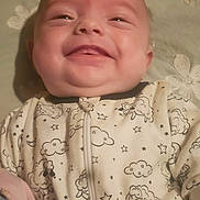 Gracie is registered to the contest to win money with this photo: baby, blanket, child, cozy, cute, expression, face, happy, head, indoors, infant, lying_down, newborn, onesie, pillow, portrait, skin, sleepwear, smiling, soft