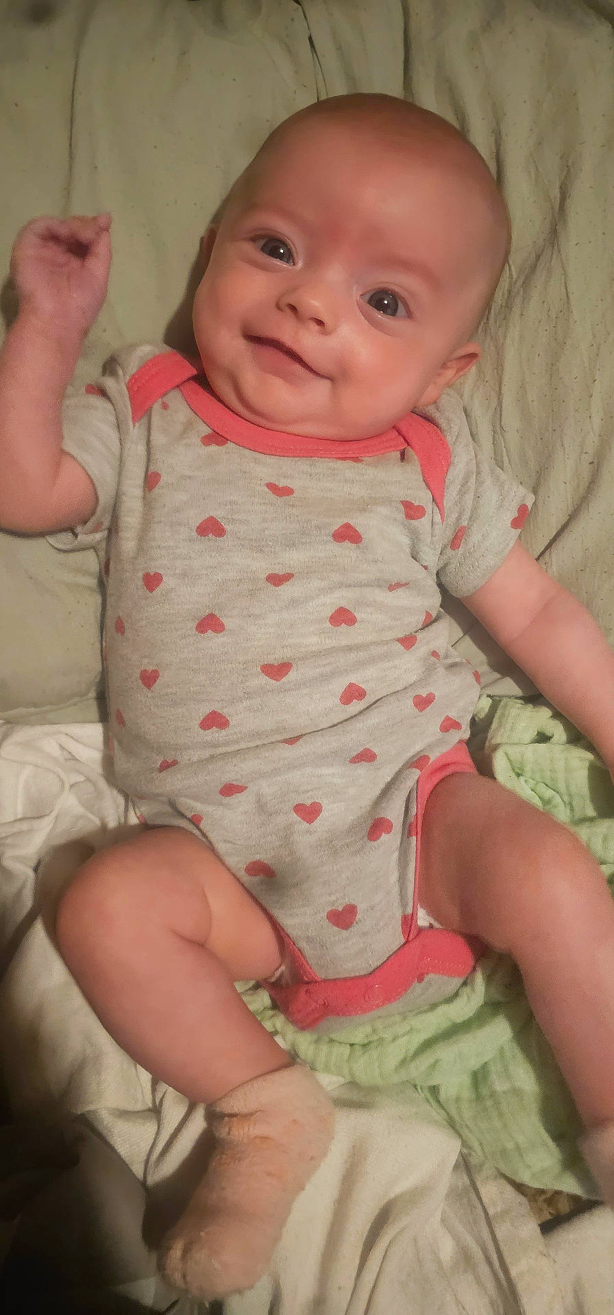 Gracie joined the competition — help win amazing prizes! adorable, baby, child, cute, expression, face, happy, head, heart_pattern, indoors, infant, lying_down, onesie, person, skin, small, smiling, sock, soft_surface, young