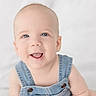 Freeman is registered to the contest to win money with this photo: baby, infant, smiling, blue_eyes, denim_overalls, happy, cute, child, portrait, face, skin, head, sitting, baby_clothes, closeup, innocence, young, bright, soft_background, indoor