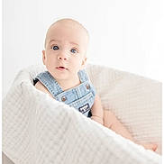 Freeman is registered to the contest to win money with this photo: baby, blanket, blue_eyes, child, clothing, curious, cute, denim_overalls, face, indoor, infant, light, looking, minimalist, portrait, sitting, skin, soft_texture, white, young