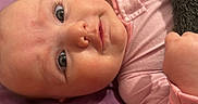 Eva is registered to the contest to win money with this photo: adorable, baby, bald, blanket, child, close_up, cozy, cute, drool, eyes, face, hand, indoor, infant, looking_at_camera, lying_down, photography, pink_outfit, portrait, soft_lighting