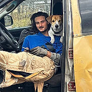 Jelly is registered to the contest to win money with this photo: person, dog, vehicle, truck, open_door, seat, window, side_mirror, ripped_pants, work_gloves, phone, companion, portrait, candid, outdoor, trees, autumn, door_hinge, relaxed, co_driver