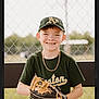 child, boy, baseball, baseball_glove, bench, cap, chain_link_fence, daylight, fence, field, green_shirt, happy, jewelry, outdoor, person, portrait, smile, sports, white_pants, young