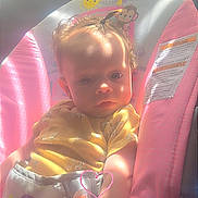 Maddelyn joined the competition — help win amazing prizes! baby, child, infant, car_seat, vehicle, sitting, portrait, face, eyes, serious_expression, sunlight, indoor, travel, pink, yellow, clothing, heart_doodle, safety_label, photograph, road_trip