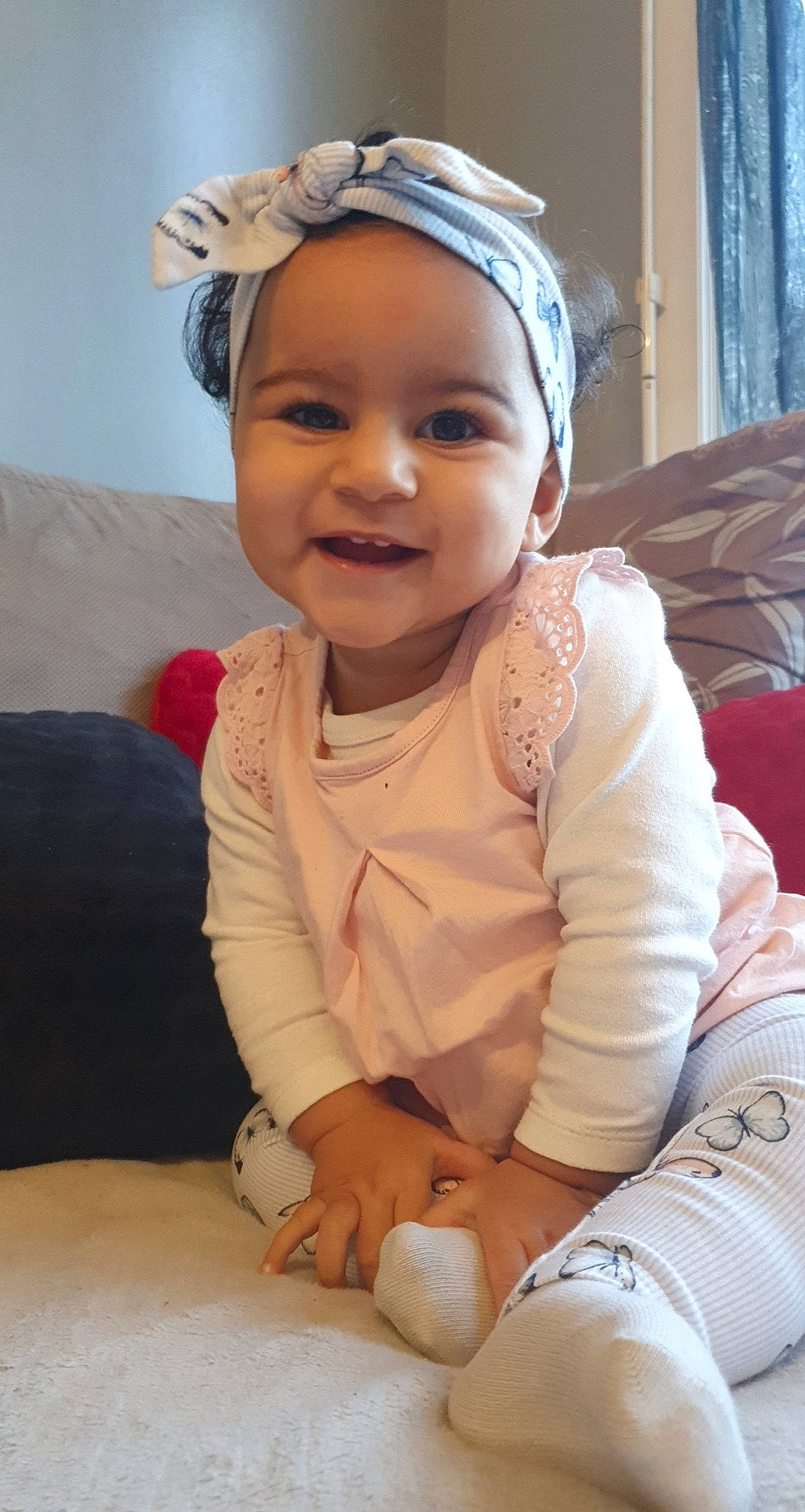 Inaya participe au concours pour gagner de l'argent avec cette photo : baby, baby_toddler_clothing, cheek, child, comfort, curtain, embellishment, hair_accessory, happy, headband, headgear, headpiece, headwear, joy, living_room, mouth, person, sitting, skin, toddler