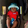 Hunter is registered to the contest to win money with this photo: baby, child, car_seat, hat, red_shirt, aqua_hat, expression, surprised, infant, footwear_free, indoor, cute, person, smile, skin, clothing, sitting, toy, pacifier, floor