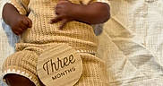 Hunter joined the competition — help win amazing prizes! baby, infant, pacifier, knitted_clothing, brown_shoes, wooden_sign, three_months, blanket, pillow, cartoon_character, lying_down, cute, child, person, indoors, soft_lighting, portrait, smiling, cozy, newborn