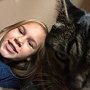 Eddie is registered to the contest to win money with this photo: child, girl, smile, braces, cat, tabby_cat, face, close_up, indoor, portrait, blond_hair, pet, animal, feline, young, happy, cute, companion, friendship, casual_clothing