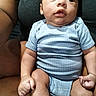baby, infant, child, person, blue_onesie, striped_clothing, sitting, lap, adult_arm, curious_expression, skin, hand, fingers, legs, torso, indoor, casual_clothing, closeup, portrait, human