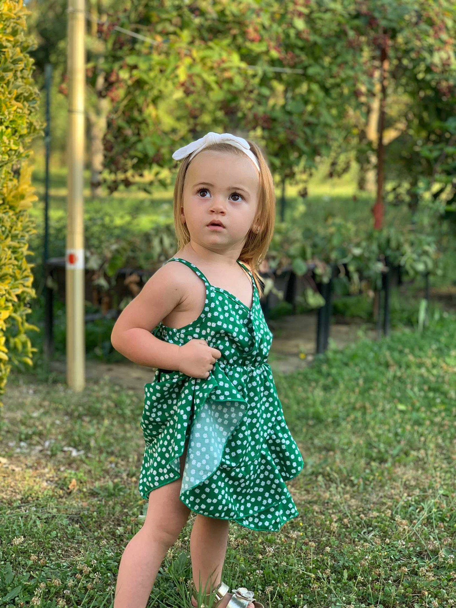 Lya participe au concours pour gagner de l'argent avec cette photo : baby_toddler_clothing, child, day_dress, dress, eye, garden, grass, grassland, hairstyle, happy, leisure, meadow, one_piece_garment, pattern, people_in_nature, person, plant, summer, toddler, tree