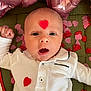 Lyam a rejoint le concours — aidez-le/la à gagner de superbes lots ! baby, infant, heart, white_shirt, confetti, pink, red, face, expression, balloon, celebration, lying_down, cute, child, portrait, skin, hand, button, fabric, closeup