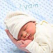 Lyam participe au concours pour gagner de l'argent avec cette photo : newborn, baby, sleeping, hat, hand, blanket, soft_texture, blue, cream_clothing, peaceful, infant, cute, portrait, closeup, cozy, resting, child, person, warmth, love