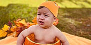 Alan joined the competition — help win amazing prizes! baby, child, pumpkin, orange_hat, blanket, outdoor, grass, fall_leaves, autumn, sitting, cute, costume, expression, nature, seasonal, holiday, funny, toddler, skin, daylight