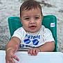 baby, child, high_chair, white_shirt, blue_text, sunglasses_graphic, hand, face, wet_hair, teal_chair, beach, sand, outdoor, person, infant, cute, smiling, portrait, summer, happy
