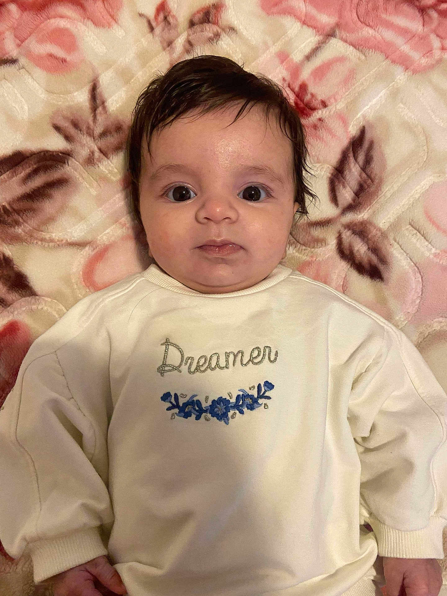 Sirine participe au concours pour gagner de l'argent avec cette photo : baby, child, infant, face, eyes, hair, sweater, clothing, blanket, floral_pattern, person, portrait, lying_down, cute, soft_texture, indoors, young_child, expression, comfortable, warm