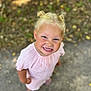 child, blonde_hair, smiling, cute, pink_dress, outdoor, happy, portrait, standing, hair_buns, face, person, young_child, daylight, nature_background, casual_clothing, feet, grass, ground, joy
