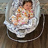 Allyson is registered to the contest to win money with this photo: baby, infant, child, bouncer, baby_seat, onesie, floral_blanket, indoor, wooden_floor, portrait, face, eyes, sitting, lying_down, colorful_clothing, patterned_fabric, home, furniture, safety_strap, adorable