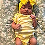 baby, infant, yellow, headwrap, polka_dot, onesie, socks, blanket, floral_pattern, cute, lying_down, small_hands, smiling, indoors, soft_texture, child, adorable, peaceful, clothing, portrait