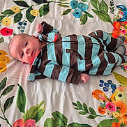 Aléssio a rejoint le concours — aidez-le/la à gagner de superbes lots ! baby, infant, striped_clothing, lying_down, blanket, floral_pattern, cartoon_animals, giraffe, elephant, lion, blue, brown, pink, green, yellow, face, person, cute, child, indoors
