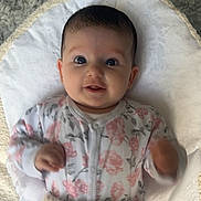 Maeve joined the competition — help win amazing prizes! baby, infant, smile, face, eyes, blanket, onesie, floral_pattern, hand, soft_texture, lying_down, cute, child, young, indoors, happy, portrait, cozy, expression, skin