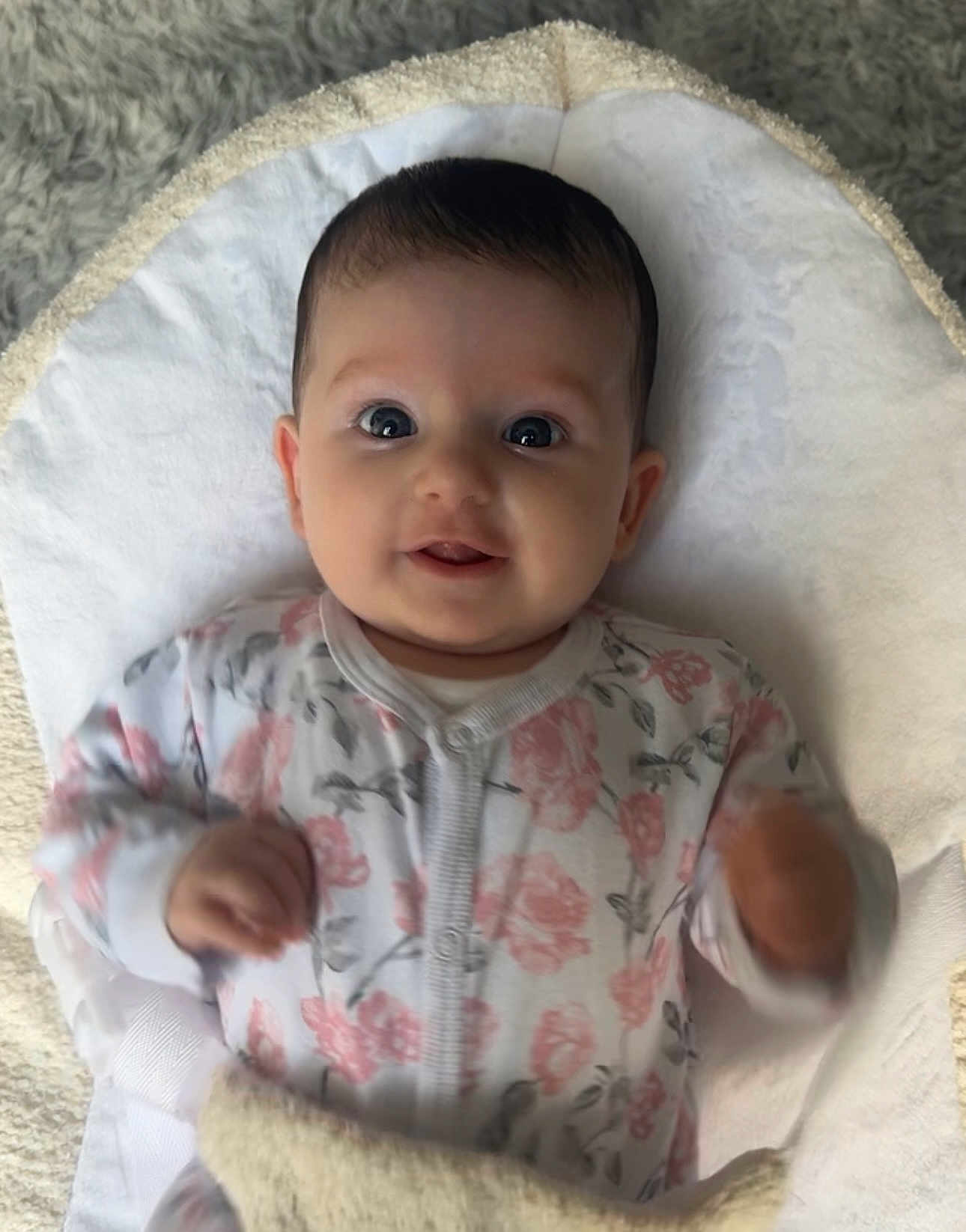 Maeve joined the competition — help win amazing prizes! baby, infant, smile, face, eyes, blanket, onesie, floral_pattern, hand, soft_texture, lying_down, cute, child, young, indoors, happy, portrait, cozy, expression, skin